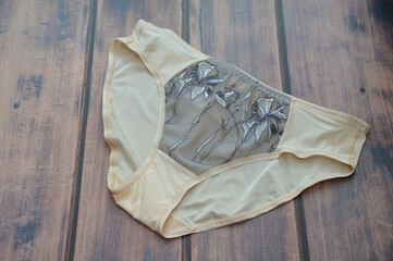 Lingerie. Modern classic beige women's slip panties with mid-waist and lace pattern.