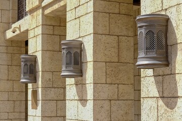 Traditional orient brass wall lanterns lights with perforated moroccan pattern for providing an enchanting ambiance outside. Vintage-style Arabic wall lamps and lanterns on villa or palace facades.