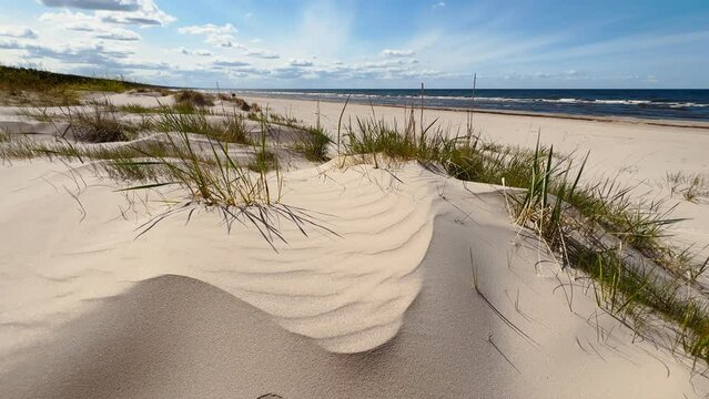 Panning up: Beautiful sandy dunes with baltic sea in the background against a blue sky