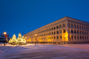 Naklejka premium Snow-covered Christmas trees decorated with garlands, street lamps and Ulyanovsk State Pedagogical University.