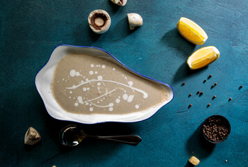 Hot mushroom soup with lime slice, black pepper and spoon served in bowl top view soup