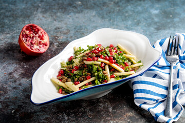kale salad with pomegranate, beans, fries served in a dish isolated on napkin side view of arab food
