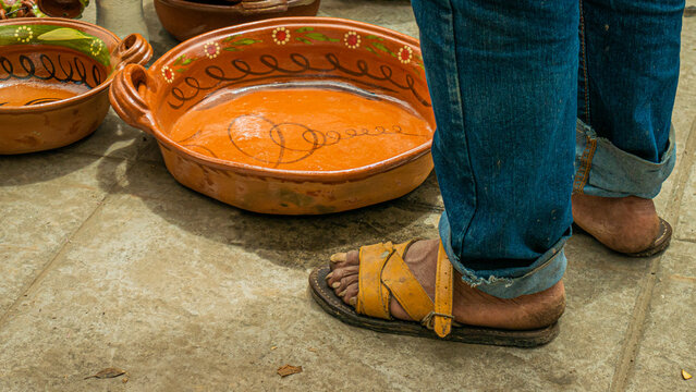 Huaraches of a man next to a casuela