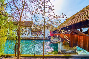 Spring in Lucerne with blooming fruit trees on the bank of Reuss river at Spreuerbrucke bridge,...