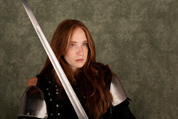 History of the Middle Ages. Portrait of a beautiful medieval female knight in armour on a green background..