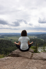 Fototapeta na wymiar Adventurous Woman in Meditation overlooking the Canadian Nature Landscape. Minnekhada Regional Park, Coquitlam, Vancouver, British Columbia, Canada.