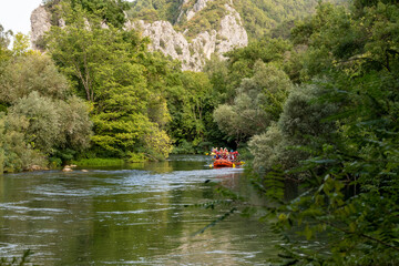 Group of tourists taking rafting tour on the Cetina river, listening to the information from the...