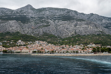 Fototapeta na wymiar Sailing out of Makarska town port, placed under high slopes and cliffs of Biokovo mountain, Croatia