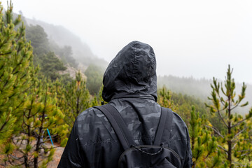 Tourist man in black coat is looking at the misty forest. Wanderlust travel concept, space for text, atmospheric epic moment, Nevado de Colima.
