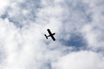 Light aircraft flies in cloudy sky on a daytime