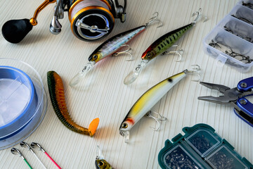 Fishing tackle - fishing spinning and baits on a light wooden background. Set of fishing tackles. 
