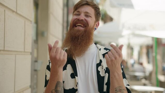 Young redhead man smiling confident doing spend money gesture at street