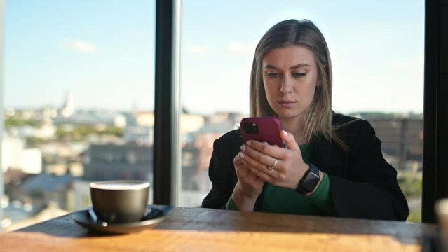 Beautiful girl against the background of the city panorama is looking at the phone. Successful business woman, 
social media marketing manager