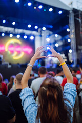 Using a smartphone in a public event, live music festival.  Summer holiday, vacation concept. 