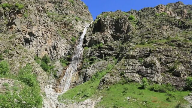 Haute cascade descendant une falaise de rochers dans les Alpes.
