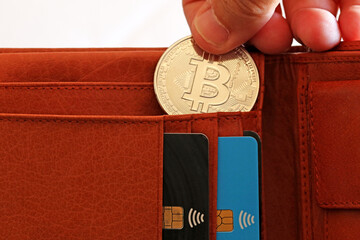 Hand putting a bitcoin coin in a wallet