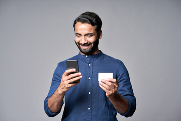 Happy indian business man holding smartphone and credit card using cell phone mobile bank app...