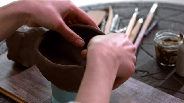 Woman potter works with clay in her home workshop, hands of the master close-up