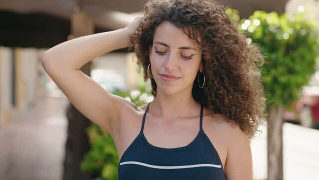 Young beautiful hispanic woman smiling confident combing hair with hands at street