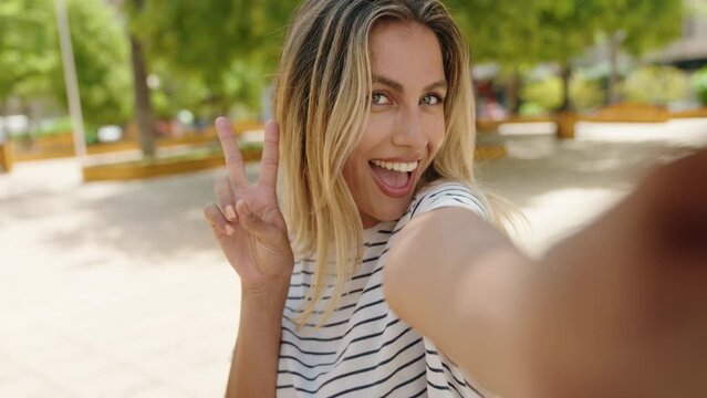 Young blonde woman smiling confident making selfie by the smartphone at park