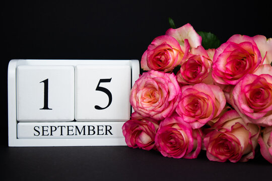 September 15 wooden calendar, white on a black background, pink roses lie nearby.Postcard with copy space. The concept of a holiday, congratulation, invitation, party, announcement, vacation,promotion