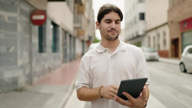 Young hispanic man using touchpad walking at street