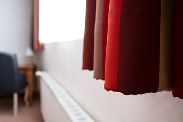 Red curtains hang on the window, in the hotel room, in a cozy interior. 