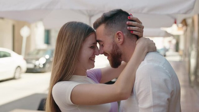 Man and woman couple hugging each other kissing at street