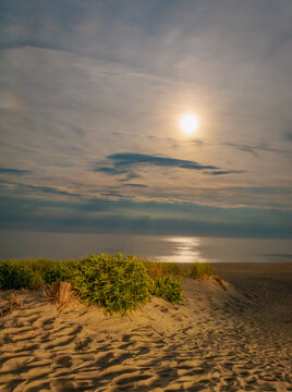 Full moon setting over ocean and beach at night, no people 
