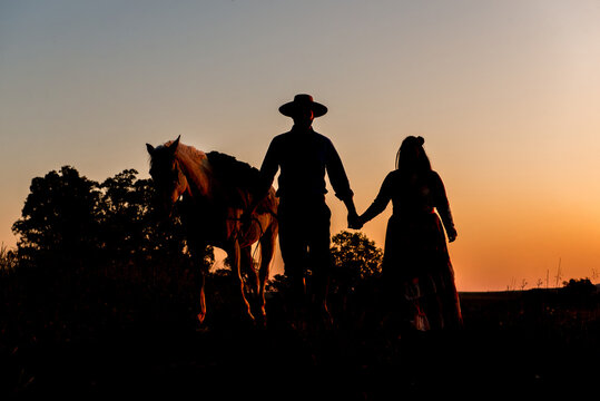 Silhouette of horse and gaucho family at sunset in South Brazil