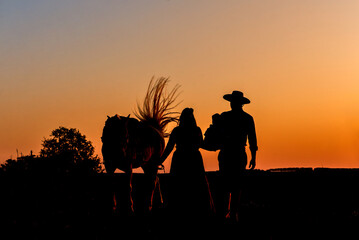 Horse and gaucho family on farm at sunset silhouette.