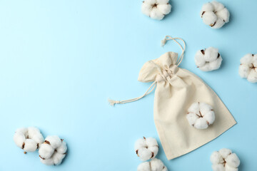 Fototapeta na wymiar Cotton eco bag and flowers on light blue background, flat lay. Space for text