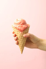 Woman holding waffle cone with delicious ice cream on pink background, closeup