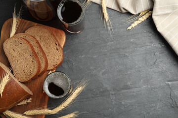 Delicious kvass, bread and spikes on black slate table, flat lay. Space for text - obrazy, fototapety, plakaty