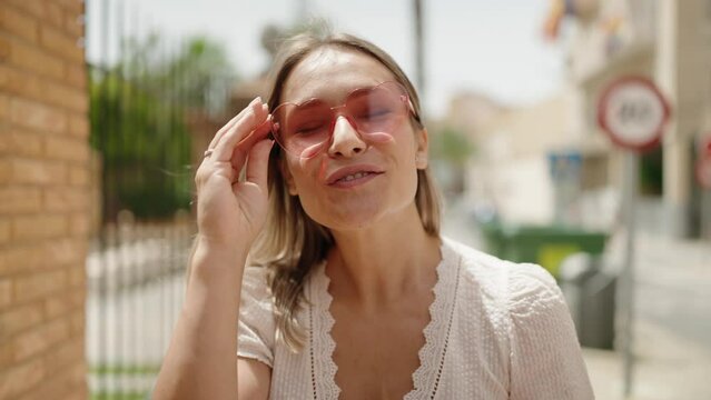 Young caucasian woman wearing heart sunglasses kissing at street