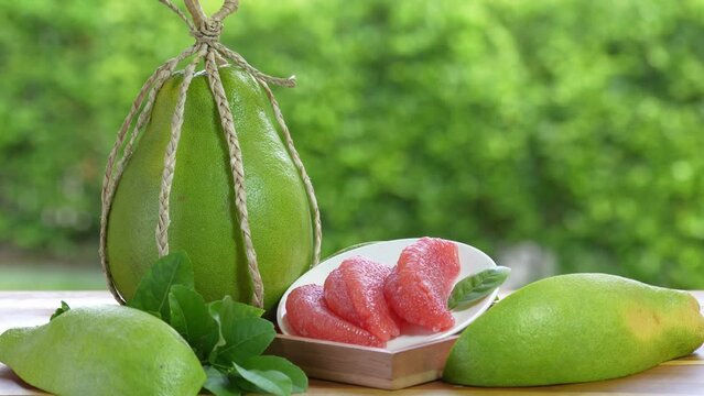 Pomelo fruit in wooden basket on blur garden background, Red Pomelo fruit with slice in wooden basket.