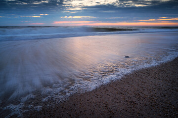 Wellen am steinigen Strand in der Nähe von Hvide Sande in Dänemark an der Nordsee kurz nach Sonnenuntergang