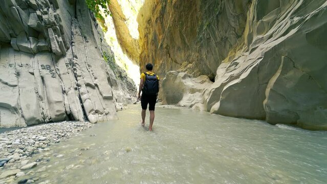 Man with bag walking on canyon through mountains.