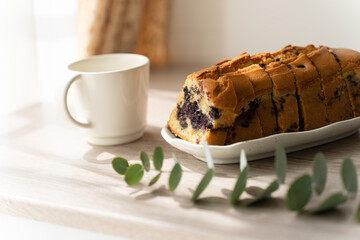 窓辺のテーブルの上の焼き菓子とマグカップ
