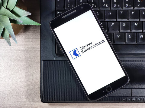 Z&uuml;rcher Kantonalbank on the smartphone screen on top on the notebook on the wooden table. Zurich Cantonal Bank is the largest cantonal bank.