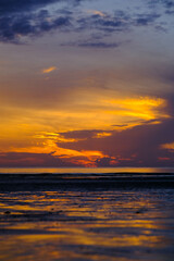 Beautiful sunset view on the beach. Colorful sea beach sunset with golden light reflected on the water surface and soft waves. Summer vacation and travel concept.