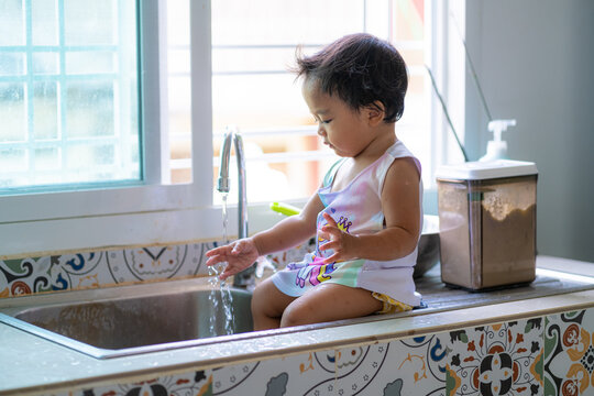 Adorable asian baby girl shower on disk sink enjoying with water