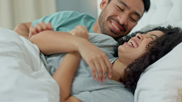 Laugh, bedroom fun and silly couple lying in bed and being playful while tickling and enjoying free time together. Man teasing woman while enjoying happy morning, cuddling and love over weekend