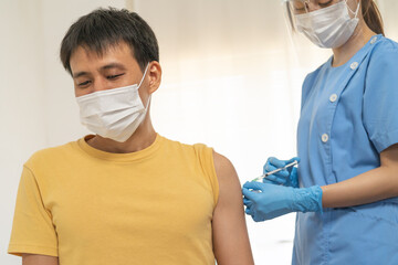 Fototapeta na wymiar Covid-19, coronavirus asian young man getting vaccine from doctor or nurse giving syringe shot to arm's patient. Vaccination, immunization, disease prevention against flu or virus pandemic concept.