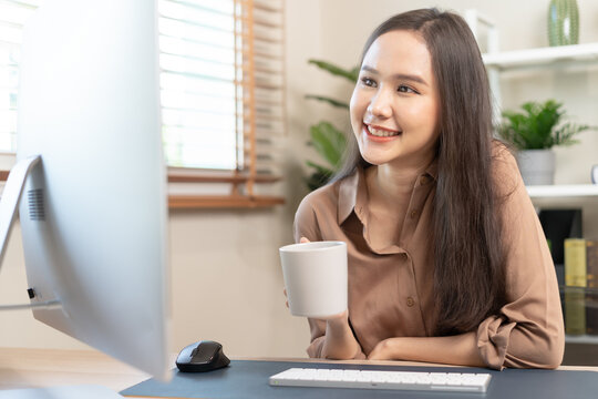 Freshness, beautiful asian young business woman holding cup coffee or drinking, freelancer working on PC compute sitting her house.Technology, social distance of work from home, office in covid-19.
