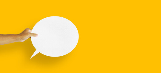 hand holding round white paper balloons speech bubbles isolated on yellow background