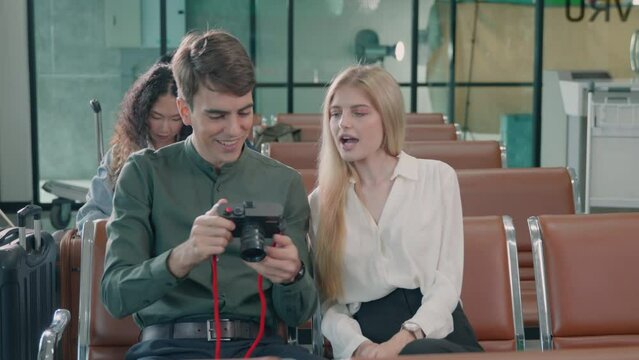 Wait boarding flight. Caucasian beautiful young loving couple smiling making selfie by their mirrorless camera while waiting for boarding in terminal hall airport, happy travel vacation concept
