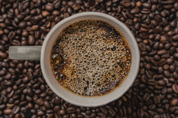 top view of cup of coffee with beans on a table with dark background