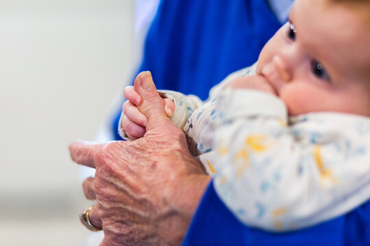 Hand of a baby holding great grandmothers finger