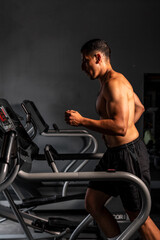 Fototapeta na wymiar High quality photography. A Latino man is running on a very modern treadmill at the gym. A muscular man performing cardio while he runs.